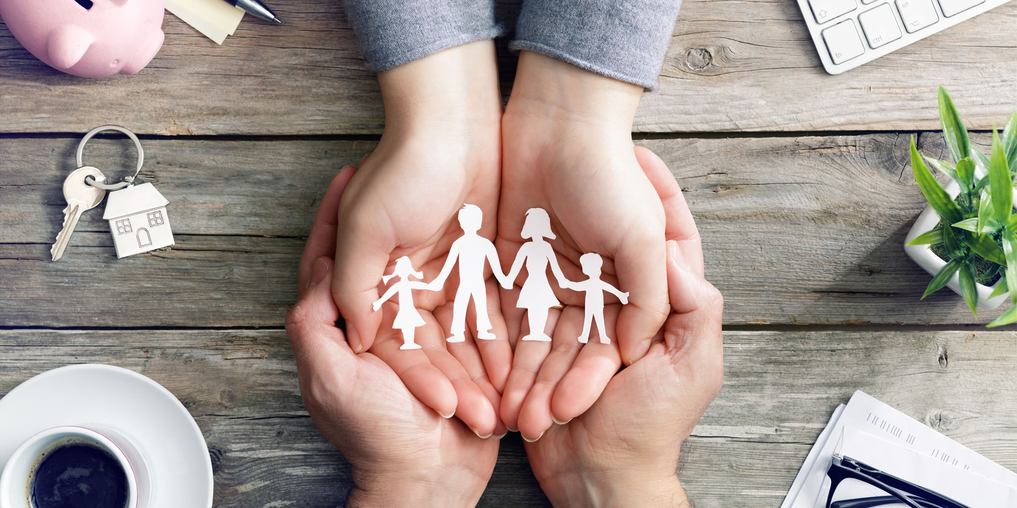 hand holding a cutout of a family and another hand holds that pair of hands