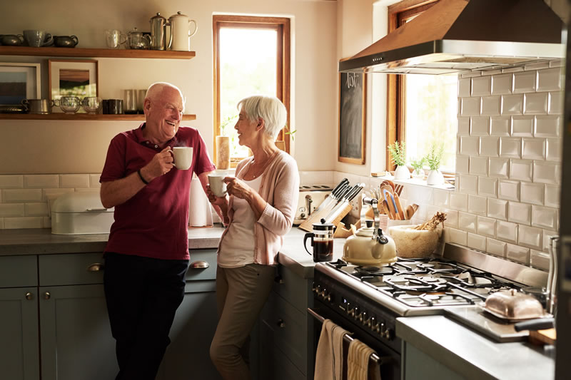mature couple discussing something in the kitchen with cups of a steaming drink in their hands