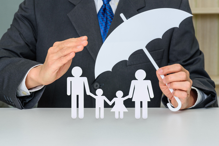2d white cutouts of a family with an umbrella over them and a 3d human hand covering them