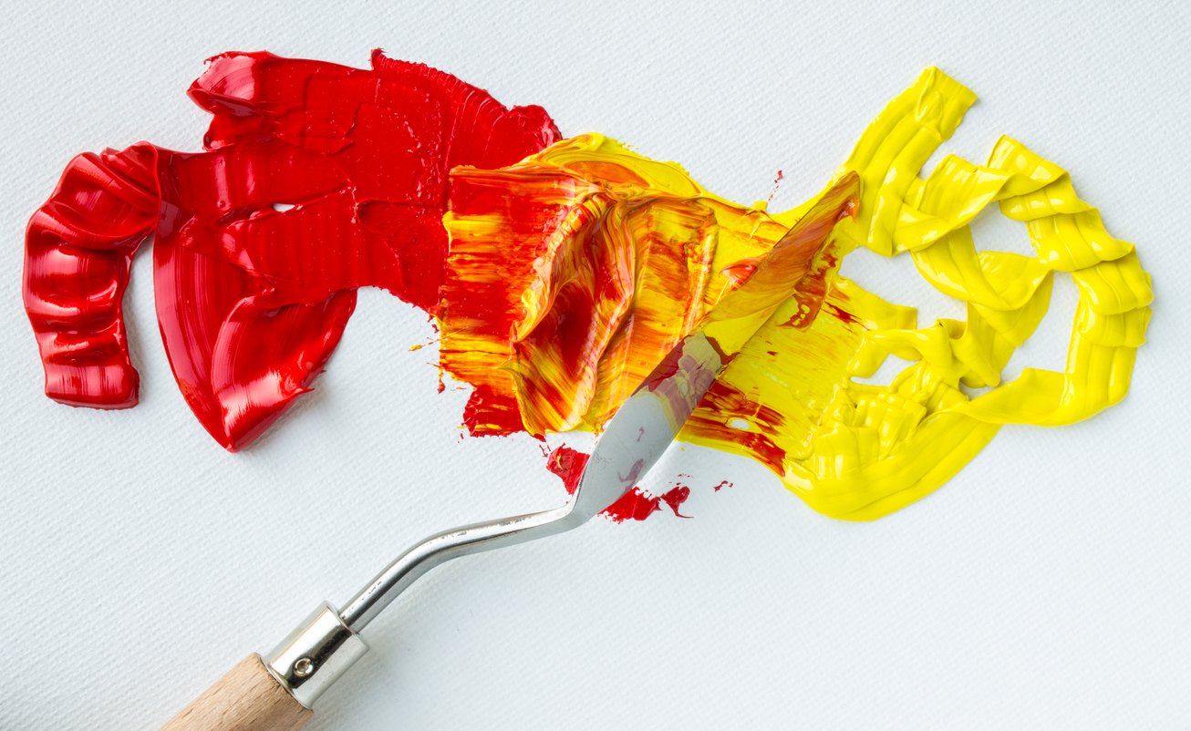 Red and yellow paint being mixed with a paintbrush