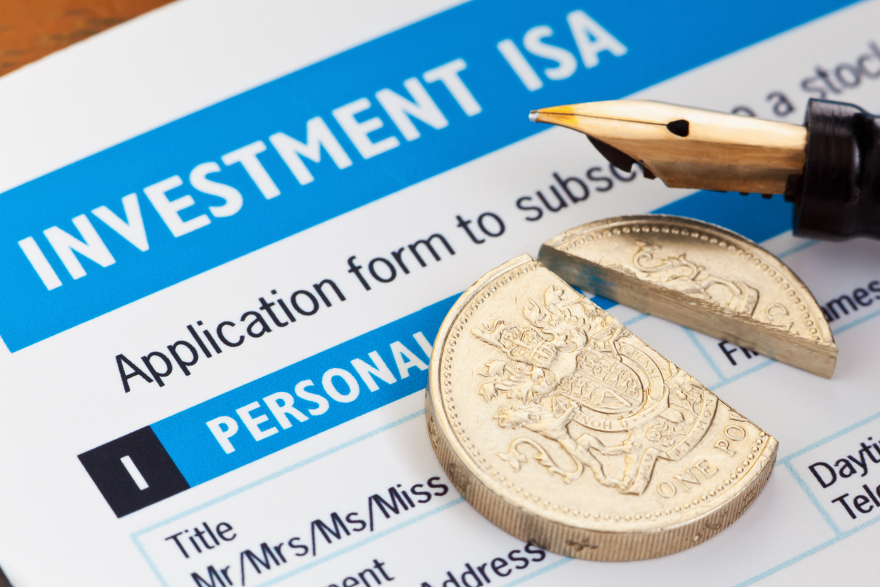 Investment ISA form with pound coin sitting on it that has been cut into two pieces