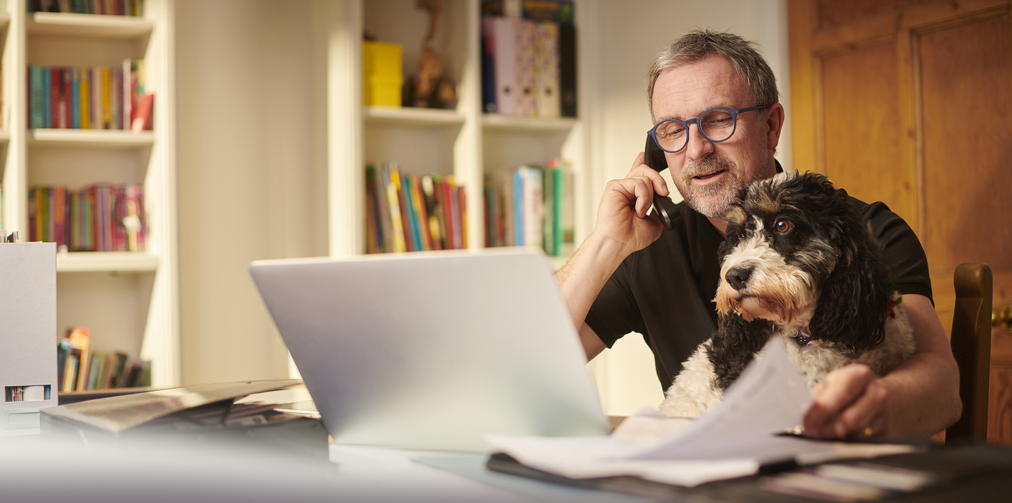 Man working from home at laptop with his dog by his side