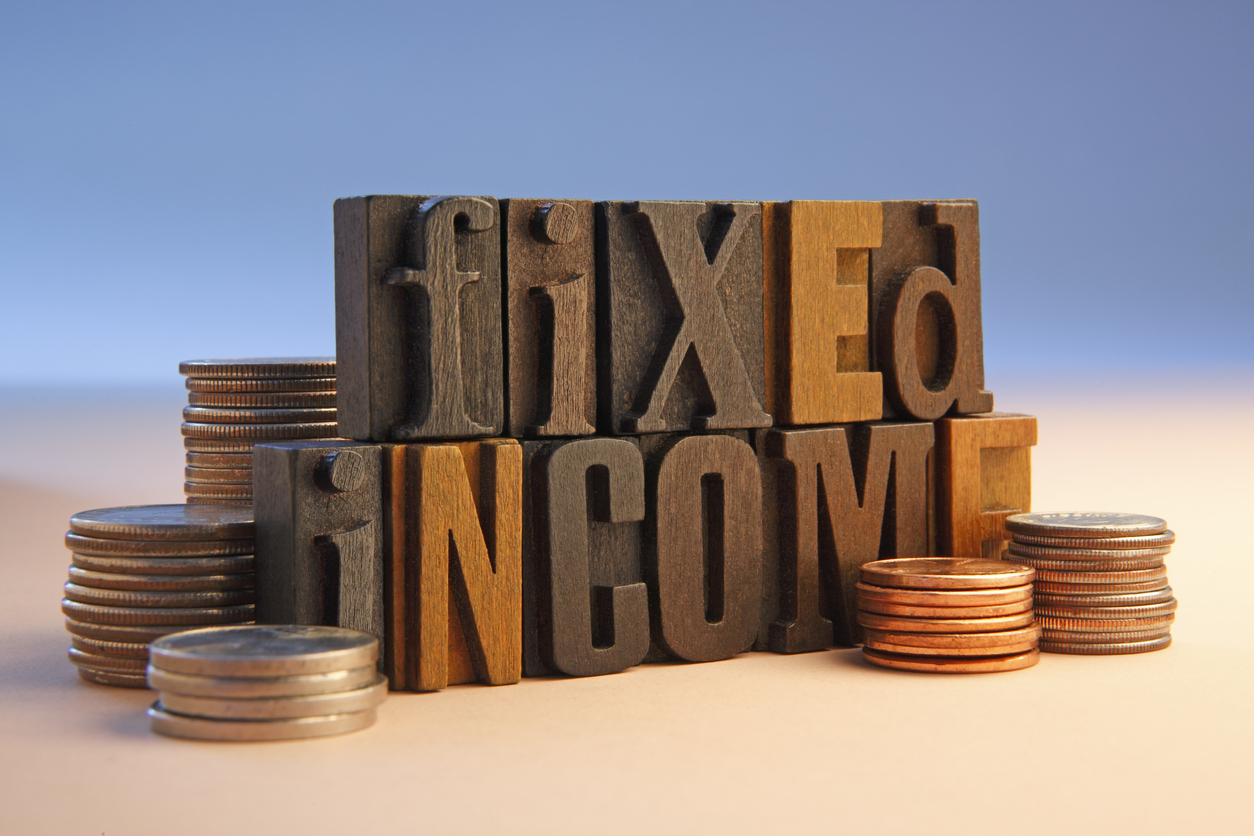 wooden block letters spelling out fixed income with a pile of coins either side