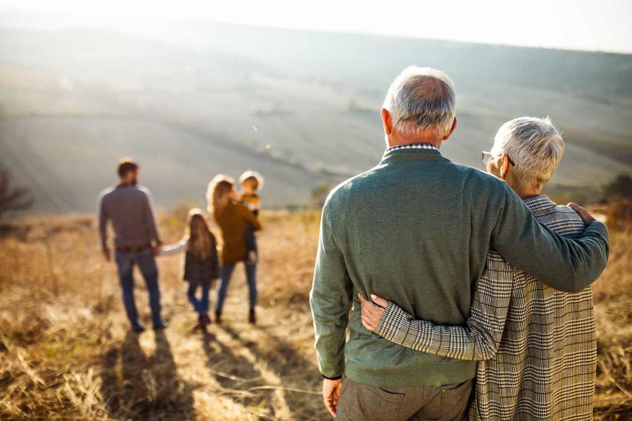 Retired couple on a hike looking over at children and grandchildren