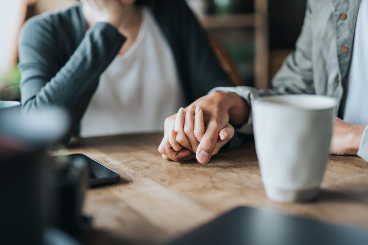 Close up of couple holding hands at a table