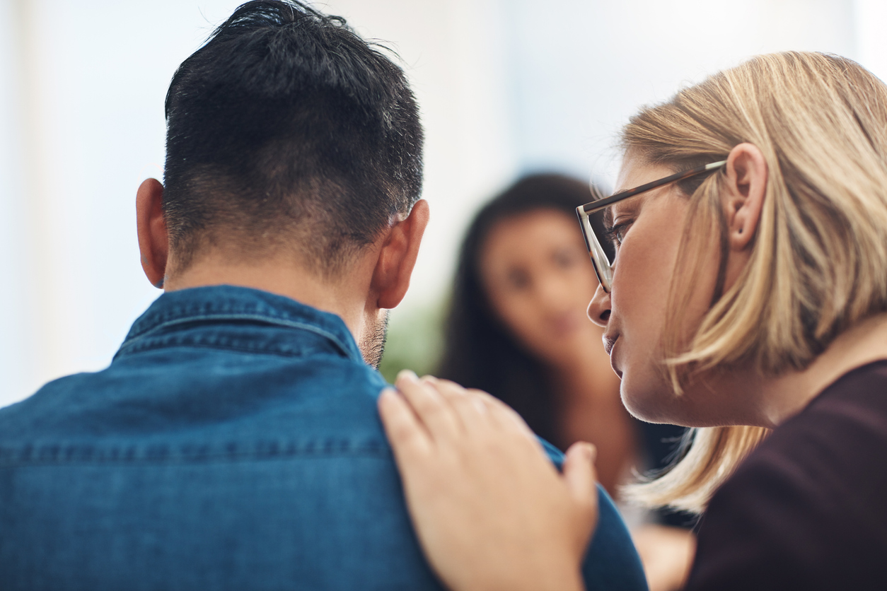 Woman comforting man with hand on his shoulder after bereavement - Bereavement benefits for unmarried couples