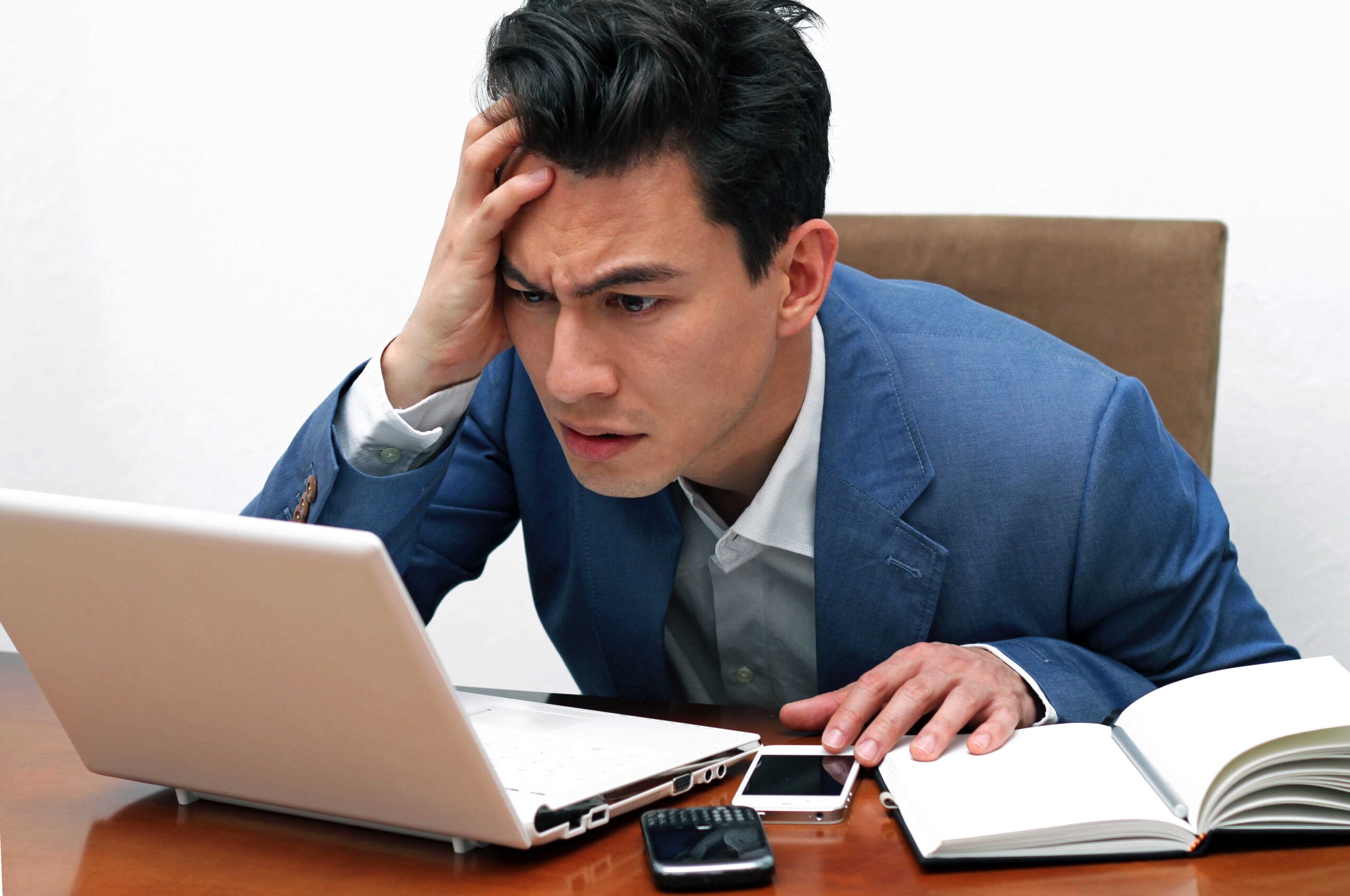 Photo of a man in a suit looking exasperated at his laptop
