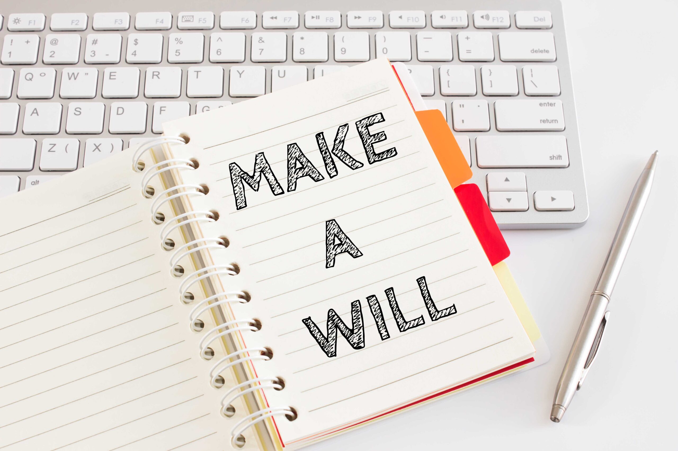 Graphic of a notebook resting on a keyboard alongside a pen, with 'Make A Will' written inside